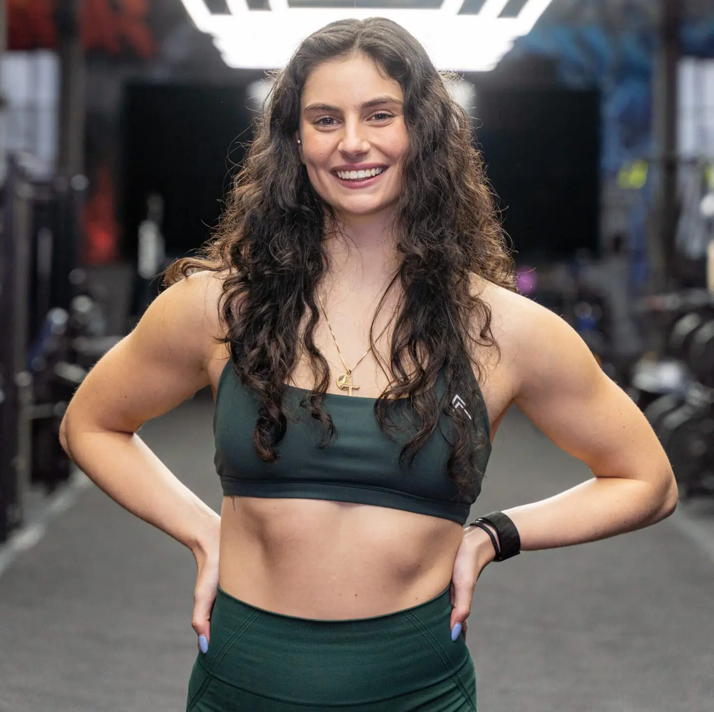 A smiling woman in workout attire at a gym.
